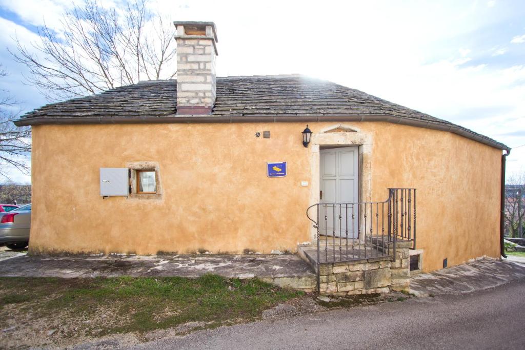 un pequeño edificio amarillo con puerta y balcón en Holiday Home Marta, en Žminj