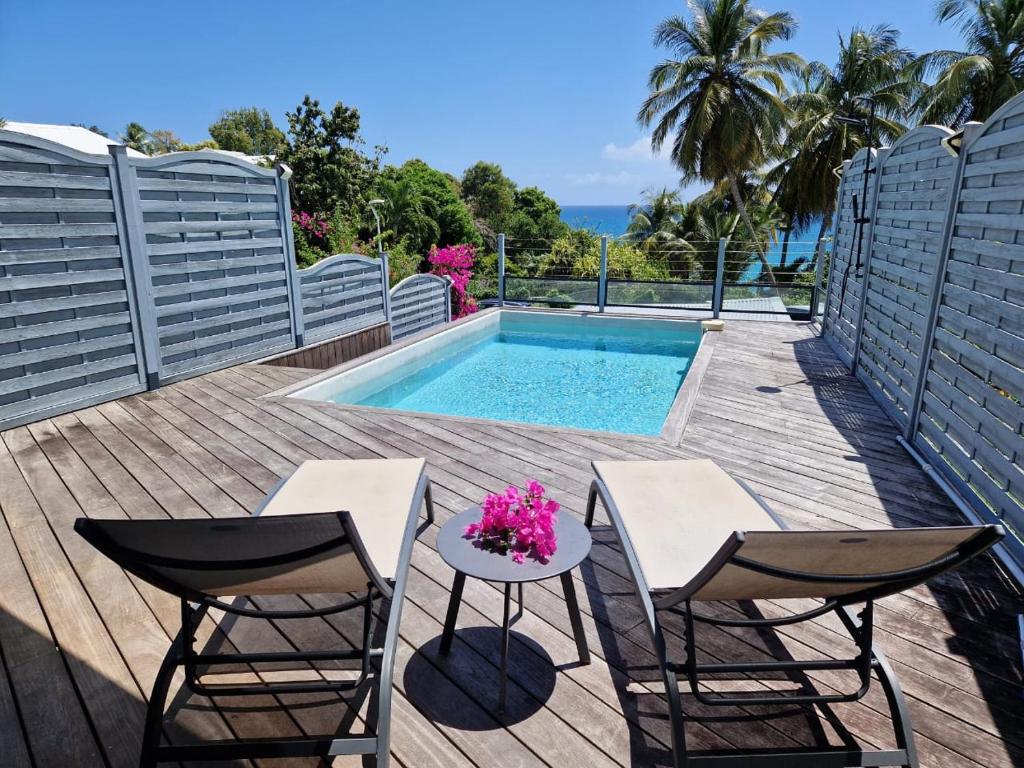 une terrasse avec 2 chaises, une table et une piscine dans l'établissement Villa Marbella - Vue mer - Piscine privée - Proche plages, au Gosier