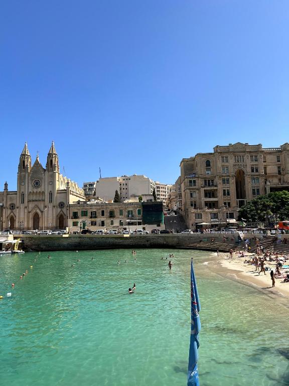 un grupo de personas nadando en el agua en una playa en Sliema Apartment in balluta bay, en Sliema