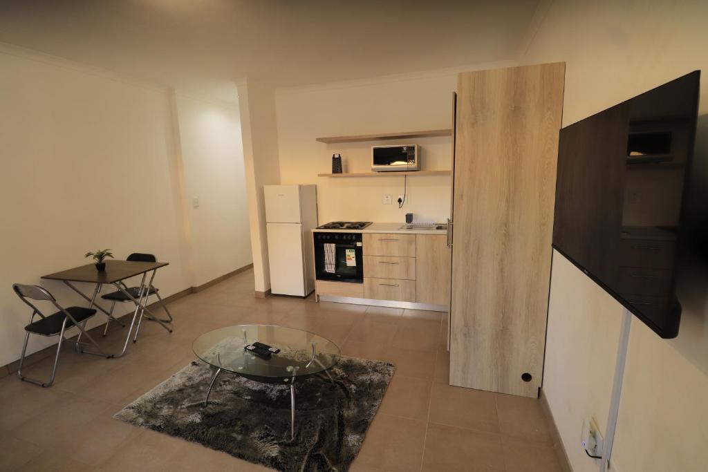 a living room with a glass table and a kitchen at Casa Decha in Windhoek