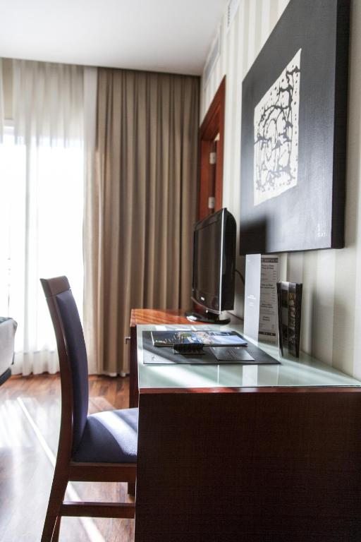 a hotel room with a desk with a television and a chair at Zenit Málaga in Málaga