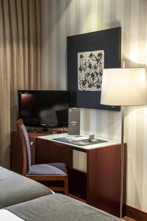 a hotel room with a desk and a lamp at Zenit Málaga in Málaga