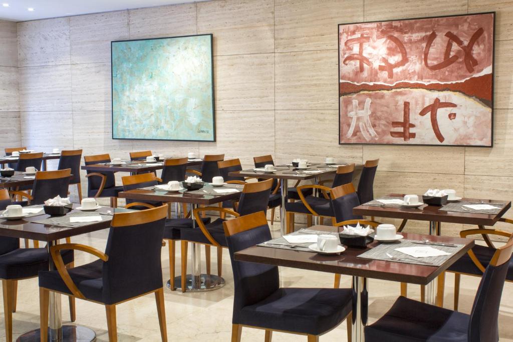 a dining room with tables and chairs and a painting at Zenit Málaga in Málaga