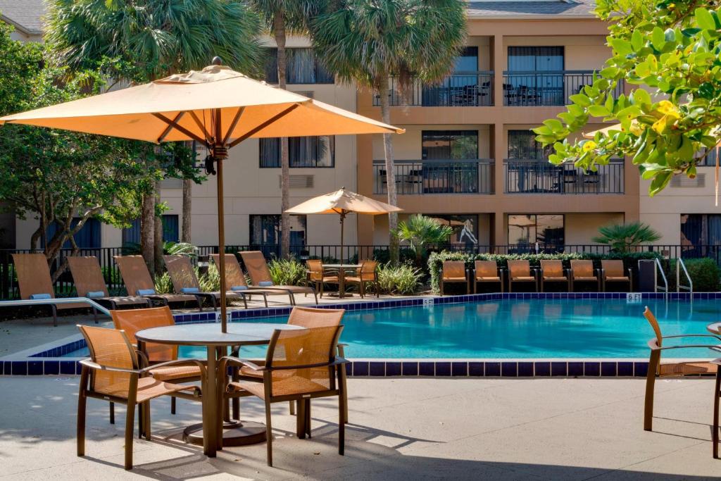 a table with chairs and an umbrella next to a pool at Courtyard by Marriott Ocala in Ocala