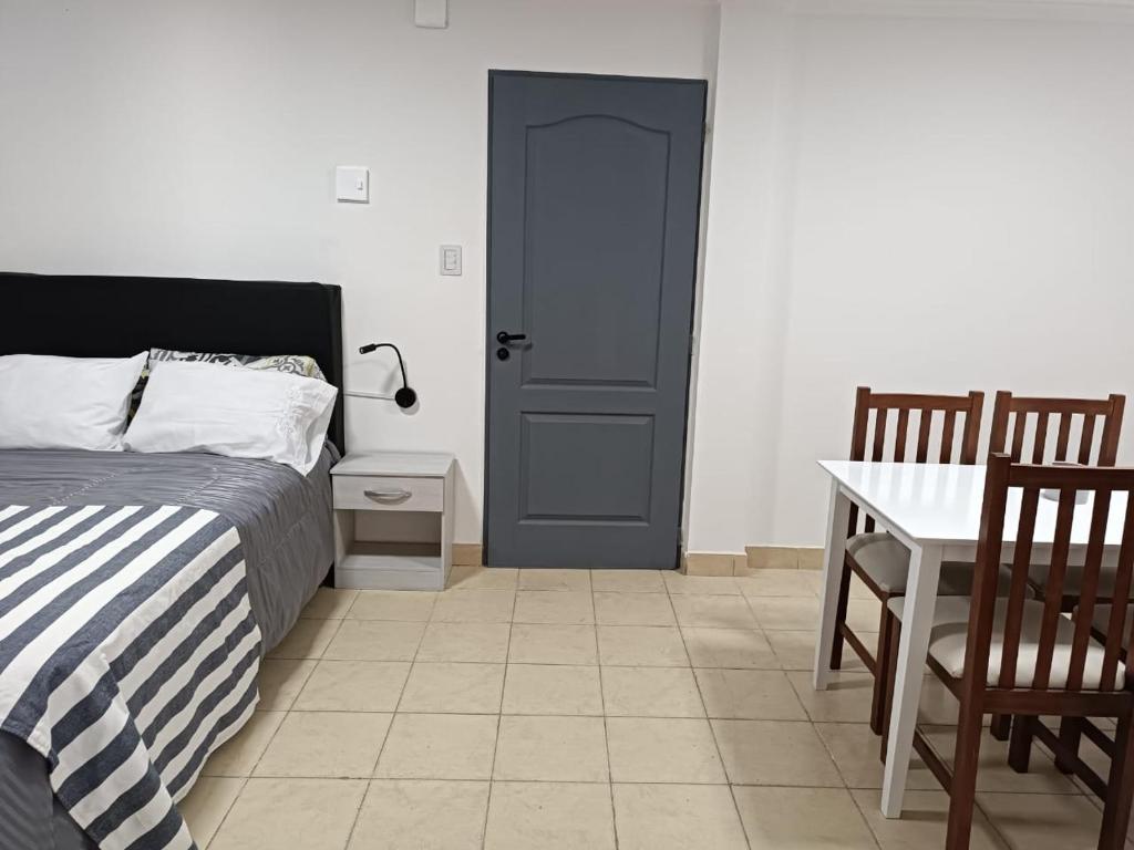 里奧加耶戈斯的住宿－Hermoso departamento en Rio Gallegos，卧室配有1张床、1张桌子和1张桌子以及椅子。