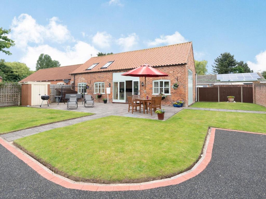 a house with a patio with a table and a lawn at Old Foundry Cottage in Burgh le Marsh