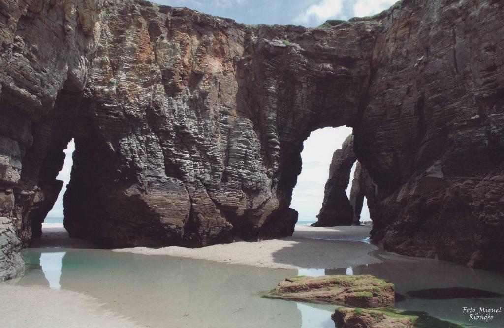 un arco en una formación rocosa en la playa en Urbanización Mar Cantábrico, en Barreiros