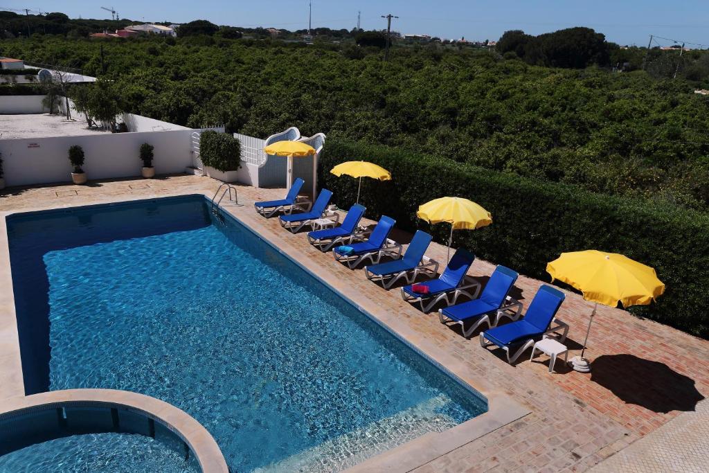 a swimming pool with chairs and umbrellas at Mira Parque in Albufeira