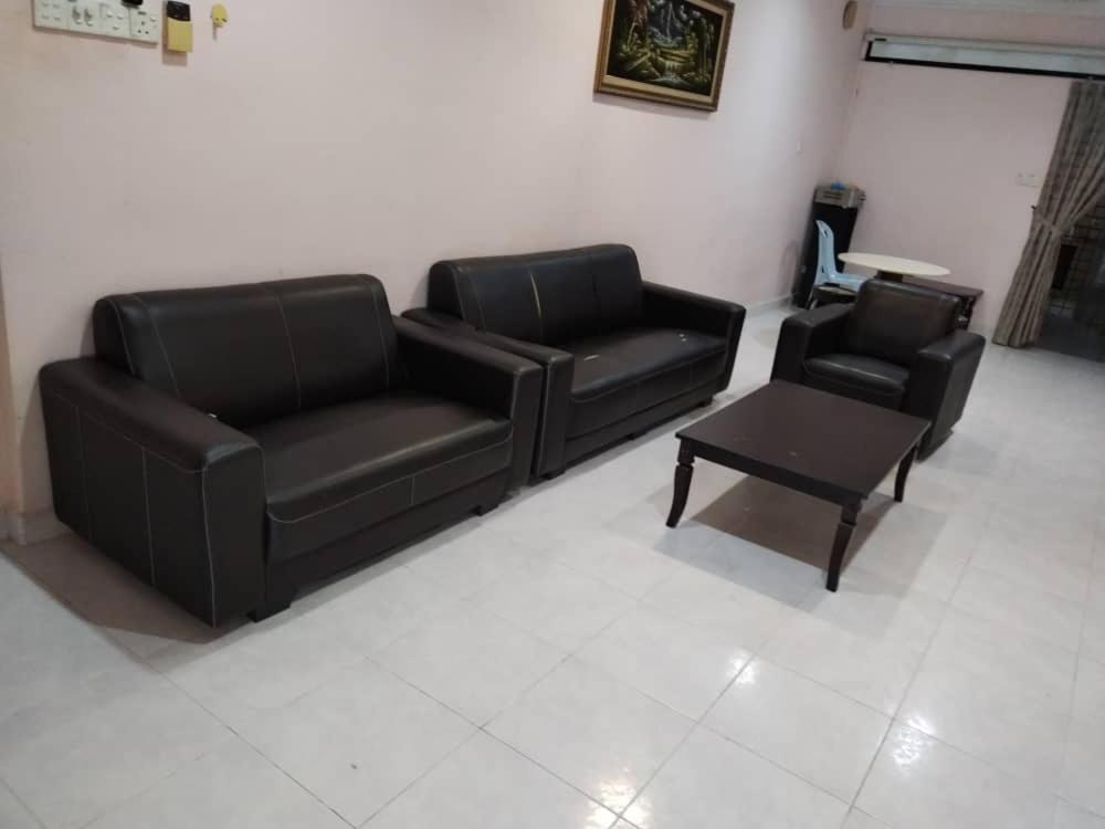 a living room with two leather couches and a coffee table at Raja Homestay Kluang in Kluang