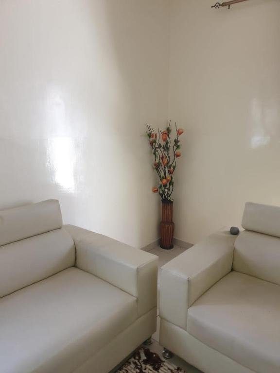 a living room with two white couches and a vase with flowers at Villa Al amine in Dakar