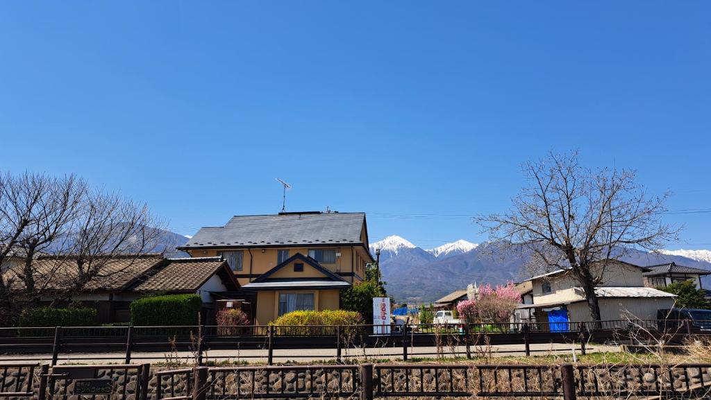 a house with a roof with mountains in the background at Shino's Farm Inn in Azumino