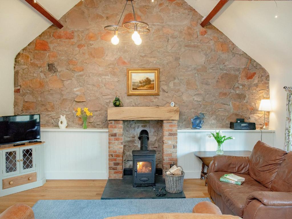 a living room with a stone wall and a wood stove at Cowslip Cottage in Templeton