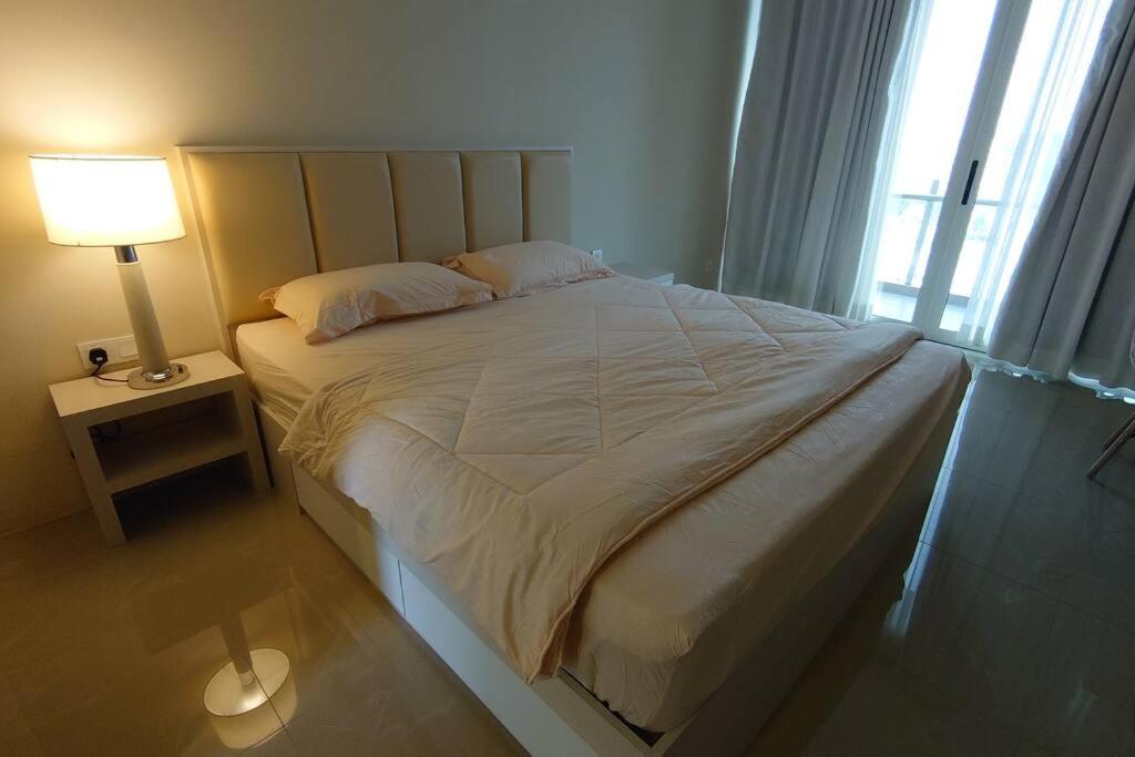 a bedroom with a large bed with a lamp and a window at Tower A, 9th Floor, No 11 in Lubuk Baja Favehotel, Apartment in Nagoya Thamrin City in Nagoya