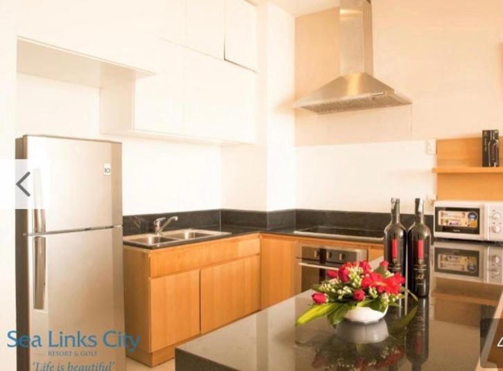 una cocina con nevera y una barra con un jarrón de flores en Sea View Condo, en Phan Thiet