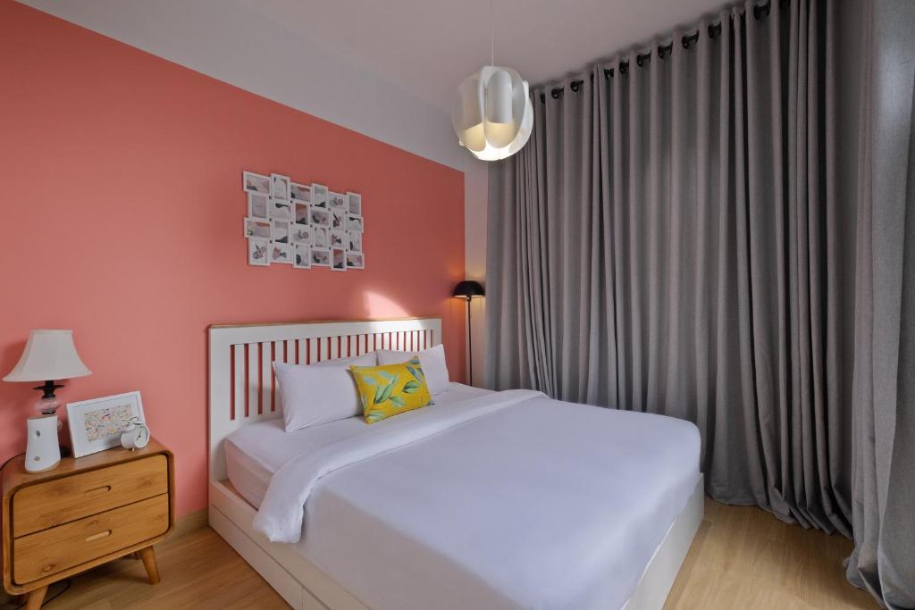 a bedroom with a white bed and a red wall at Roemah Renjana Rosie Makassar in Makassar