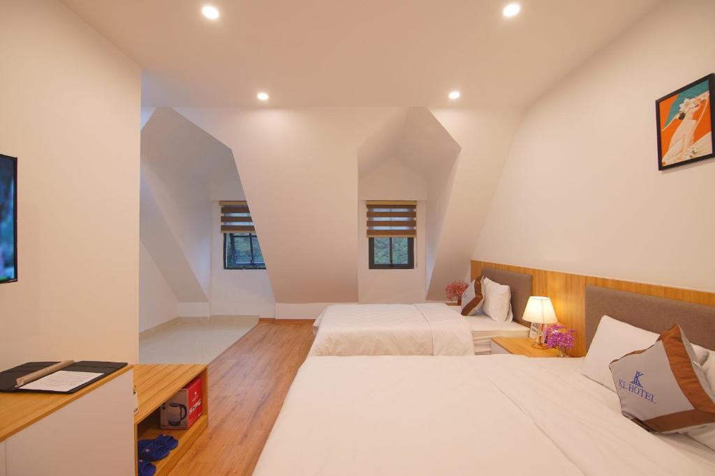 - une chambre mansardée avec 2 lits et un bureau dans l'établissement KL HOTEL HA LONG, à Hạ Long
