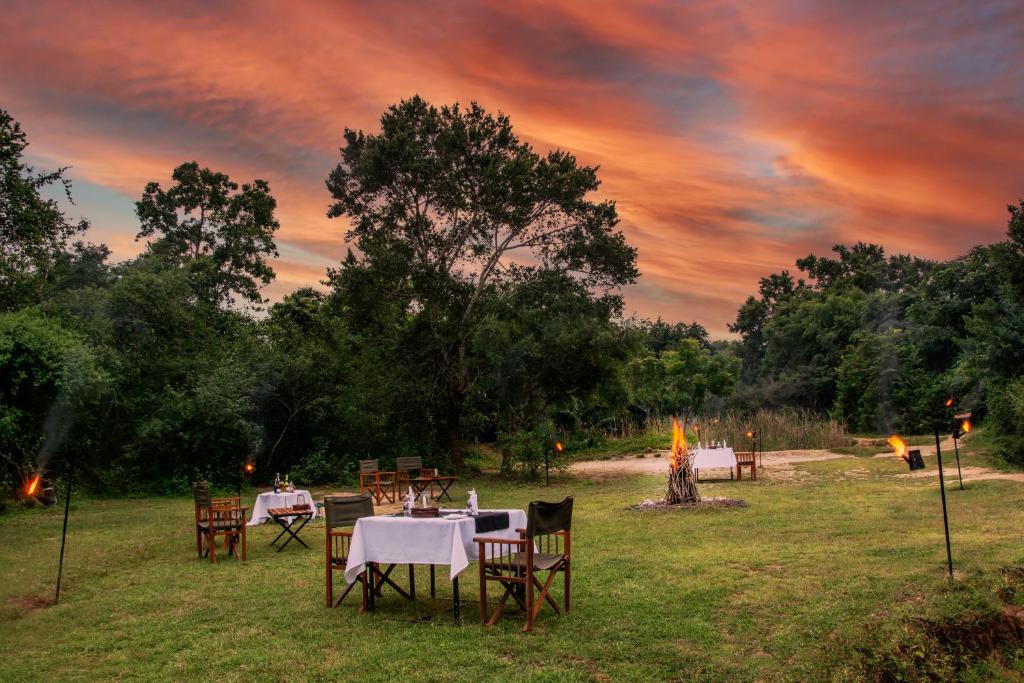 a group of tables and chairs in a field at sunset at Mahoora Yala - by Eco Team in Yala