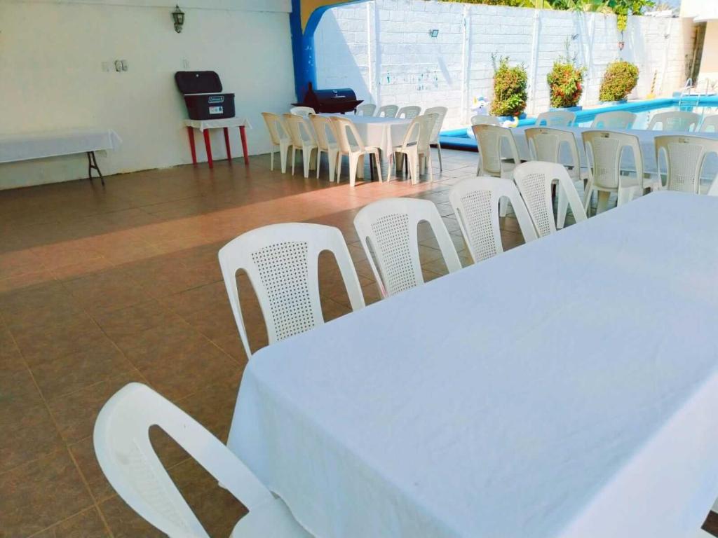 un groupe de tables et de chaises blanches dans une pièce dans l'établissement alberca Blass, à Coatzacoalcos