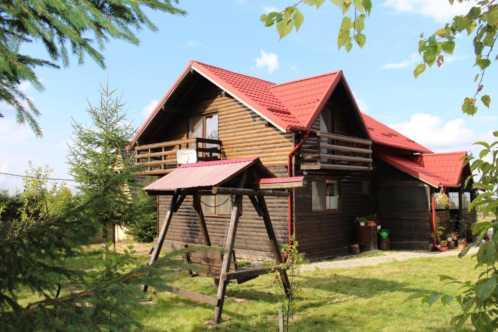 a log cabin with a red roof at Pensiunea turistica Adler in Bălceşti
