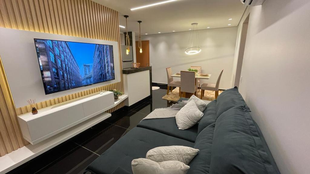 sala de estar con sofá y TV en la pared en Condomínio encantador de luxo en Goiânia