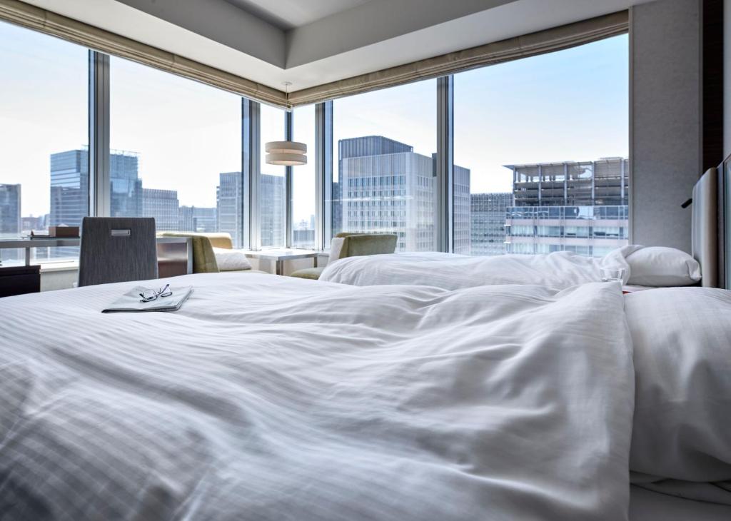 Cama blanca en habitación con ventana grande en Hotel Metropolitan Tokyo Marunouchi en Tokio