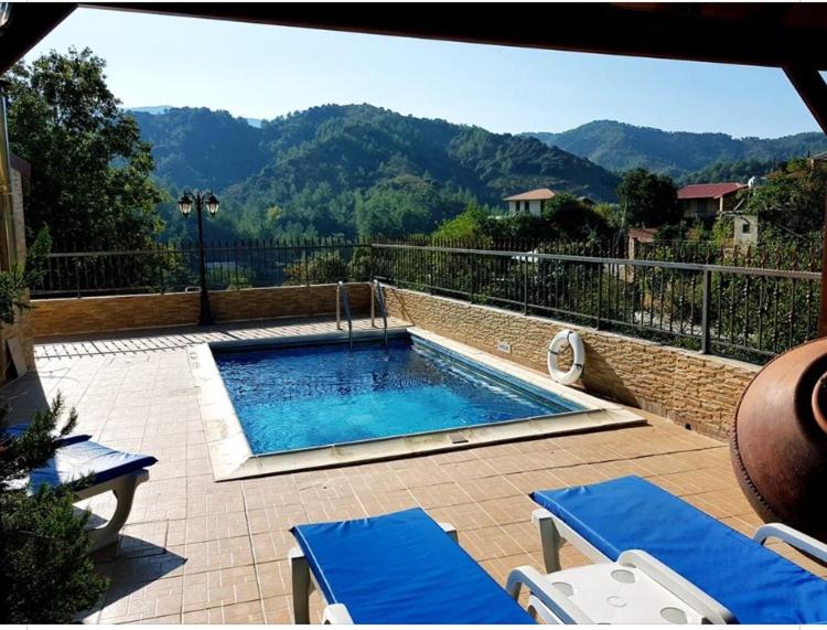 a swimming pool with two blue lounge chairs at The Love Holiday House in Tris Elies