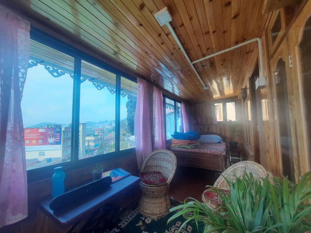una habitación con 2 sillas y una habitación con ventanas en Neora Backpackers Hostel en Darjeeling