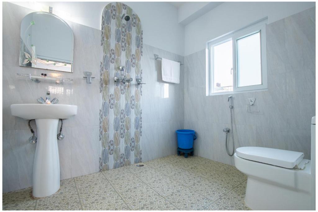 un bagno con lavandino, water e specchio di Hotel Tulip Pokhara Inn a Pokhara