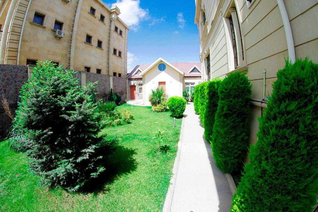 einen Hof mit Bäumen und einem Gebäude und einem Bürgersteig in der Unterkunft All Seasons Hotel Baku in Baku