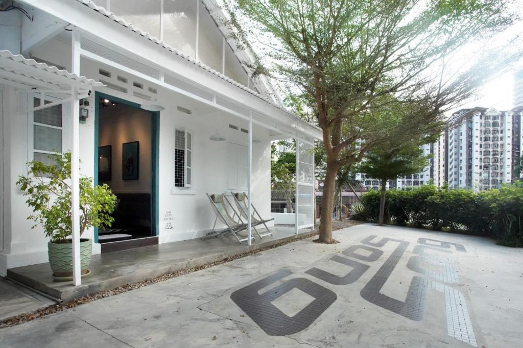 a white house with a tree and chairs on a patio at Stay SongSong Mount Erskine in George Town