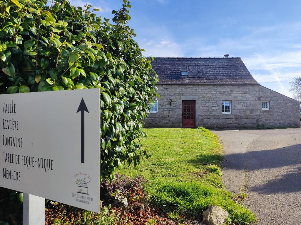 ein Schild vor einem Steingebäude mit einem Haus in der Unterkunft Les Gites de TY Dreux Monts d'arrée in Saint-Thégonnec