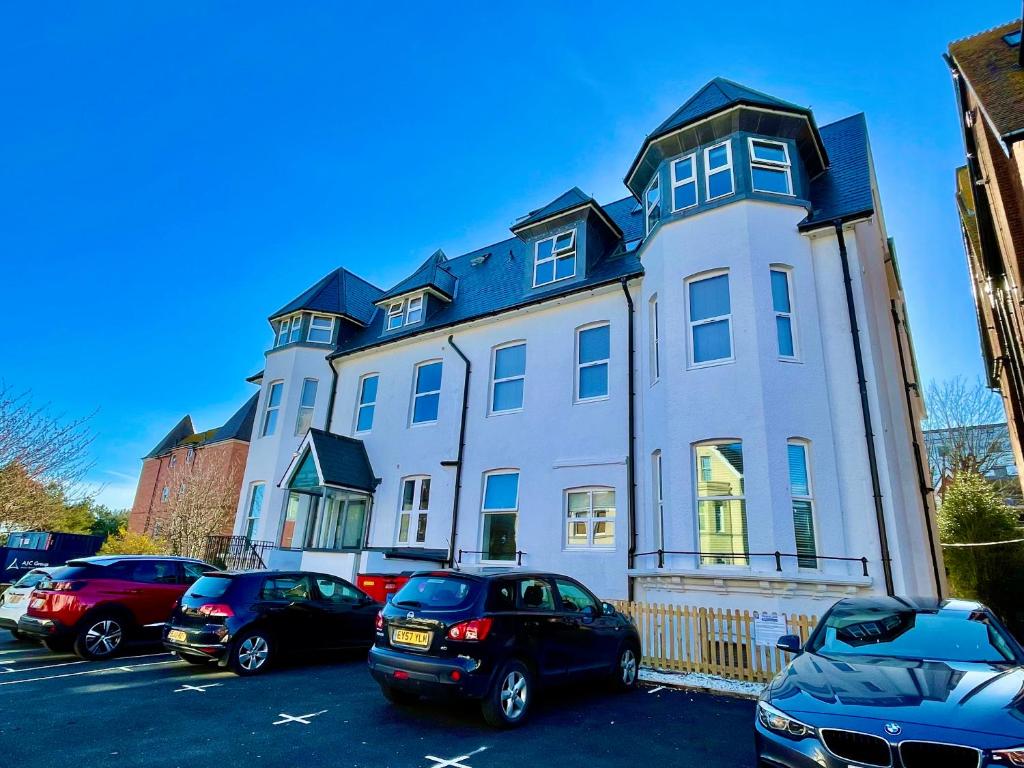 una gran casa blanca con coches aparcados en un aparcamiento en Tower House Apartments en Bournemouth