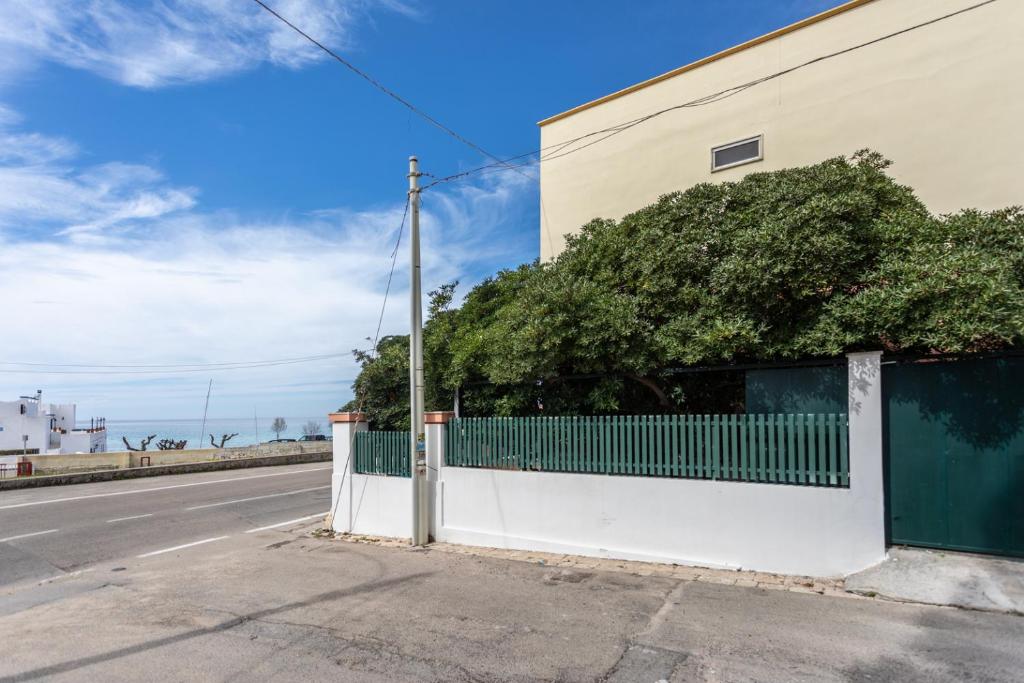 uma cerca ao lado de um edifício ao lado de uma rua em Villetta Bianca em Gallipoli