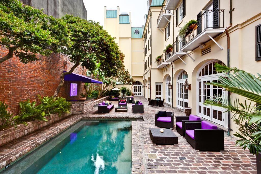 a courtyard with a swimming pool and chairs and a building at Hotel Le Marais in New Orleans