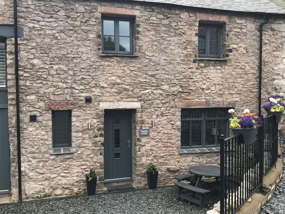 une maison en pierre avec une table de pique-nique devant elle dans l'établissement Modern 3 Bed Barn Conversion in Great Urswick, à Great Urswick