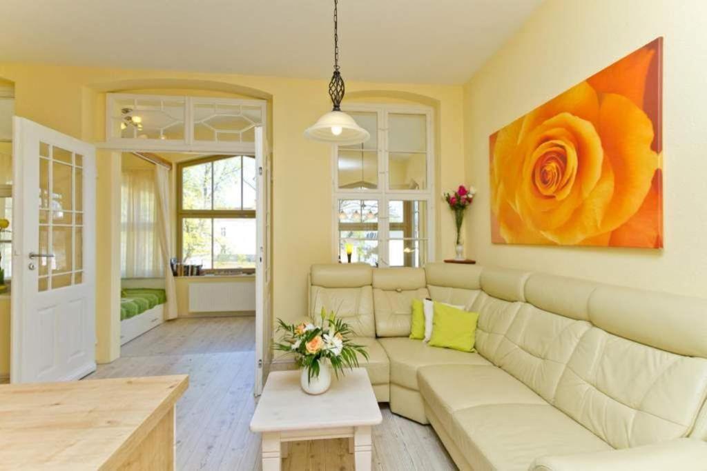 ein Wohnzimmer mit einem Sofa und einem Blumengemälde an der Wand in der Unterkunft Villa Waldschloss, App 05 in Heringsdorf