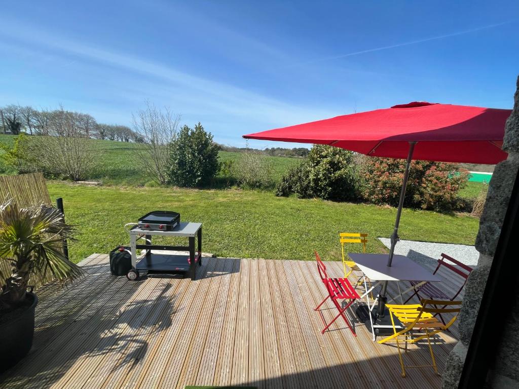 une terrasse avec un parasol rouge, une table et des chaises dans l'établissement Gîtes d'Izel n°2, à Ploemel