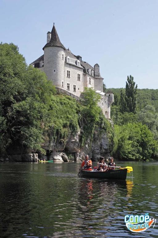 a group of people in a boat on a river with a castle at Gîte "le haut des Poujades" in Reilhaguet