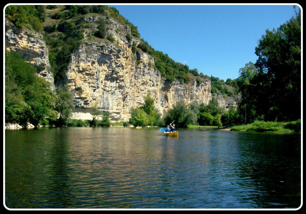 a boat on a river in front of a mountain at Gîte "le haut des Poujades" in Reilhaguet