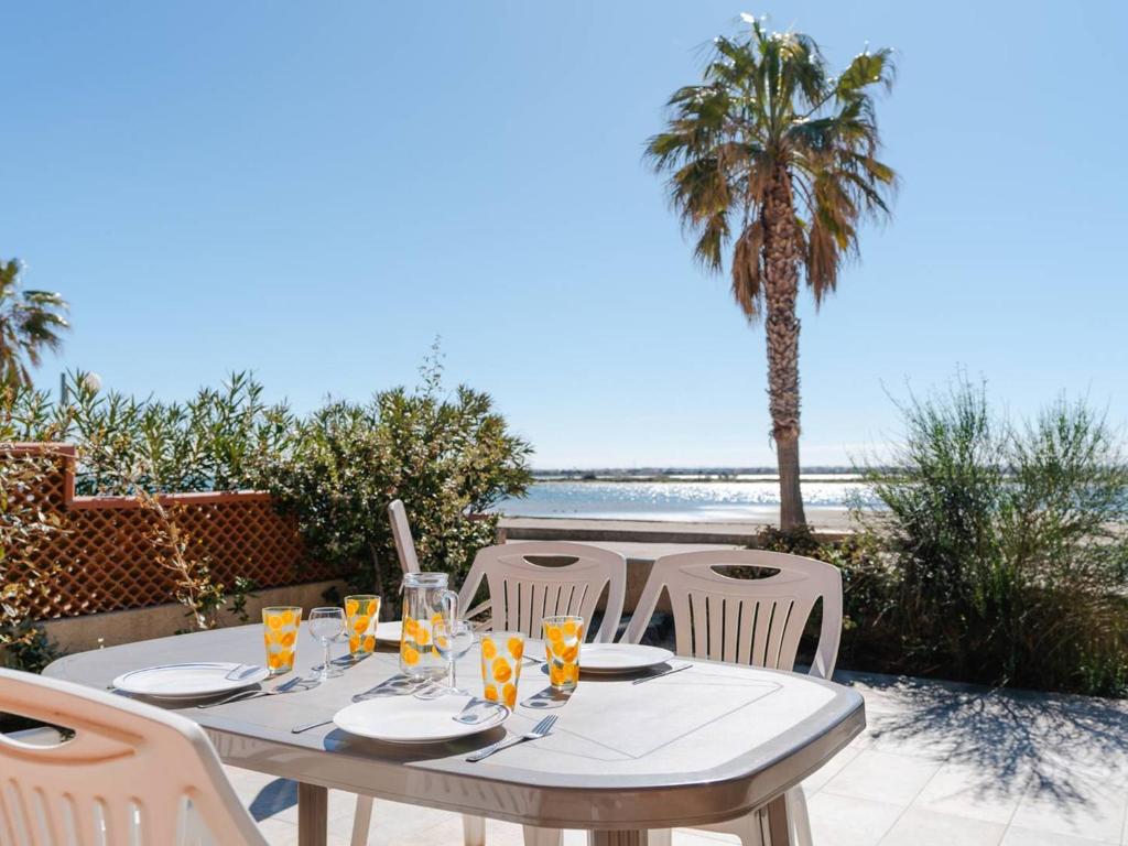 a table with chairs and a table with a view of the beach at Villa Gruissan, 3 pièces, 6 personnes - FR-1-409A-20 in Gruissan