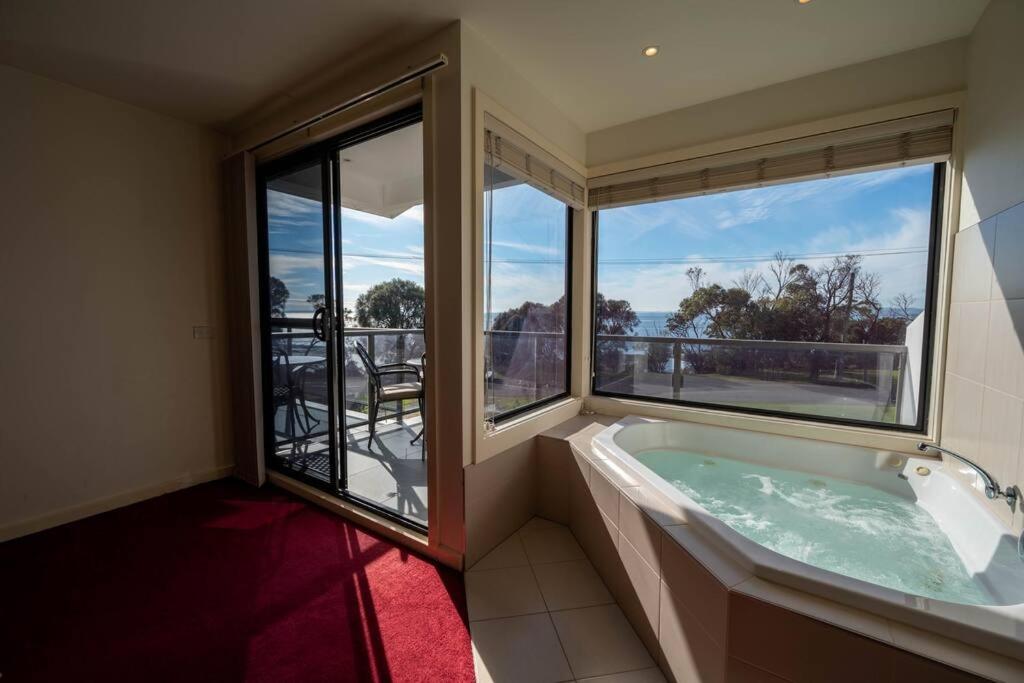 a bath tub in a room with a large window at Moonlight Bay and Gallery Ocean View King Suite #3 in Newhaven