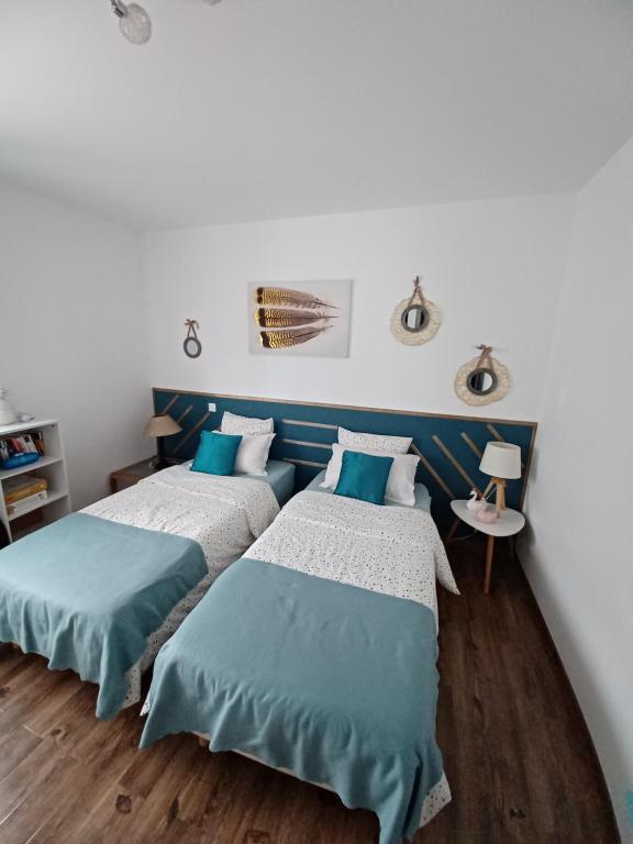 カロンザナにあるmaison cosy climatisée avec piscine et jardinの白と青の部屋のベッド2台