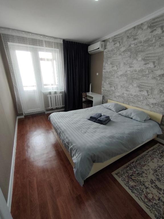 1 dormitorio con 1 cama grande y pared de ladrillo en 2 комнатная Нурсат вдоль Аллеи, en Shymkent