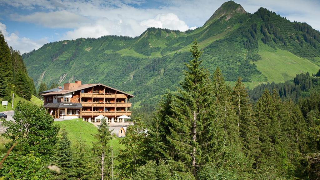 a house on a hill in front of a mountain at Das alpine Lifestyle Berghotel Madlener in Damuls