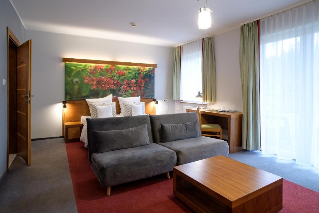 een woonkamer met een bank en een tafel bij Hotel Szarlota - Kompleksowo na Kaszubach in Kościerzyna