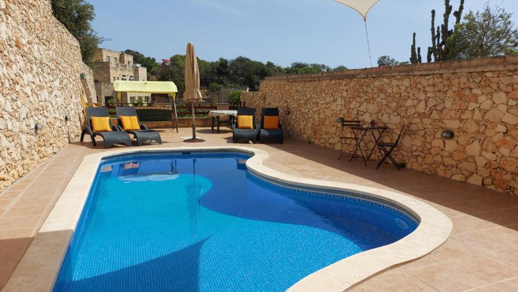 una piscina con acqua blu di fronte a un muro di pietra di Happy and Healthy Gozo B&B HOUSE a Victoria