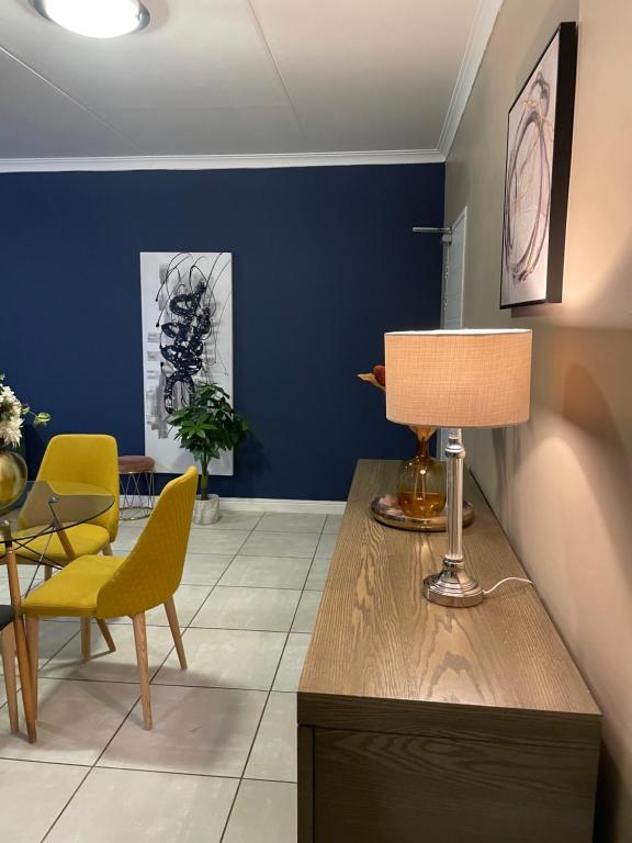 ein Wohnzimmer mit blauen Wänden und einem Tisch mit einer Lampe in der Unterkunft The Blyde 449 Reformity in Pretoria