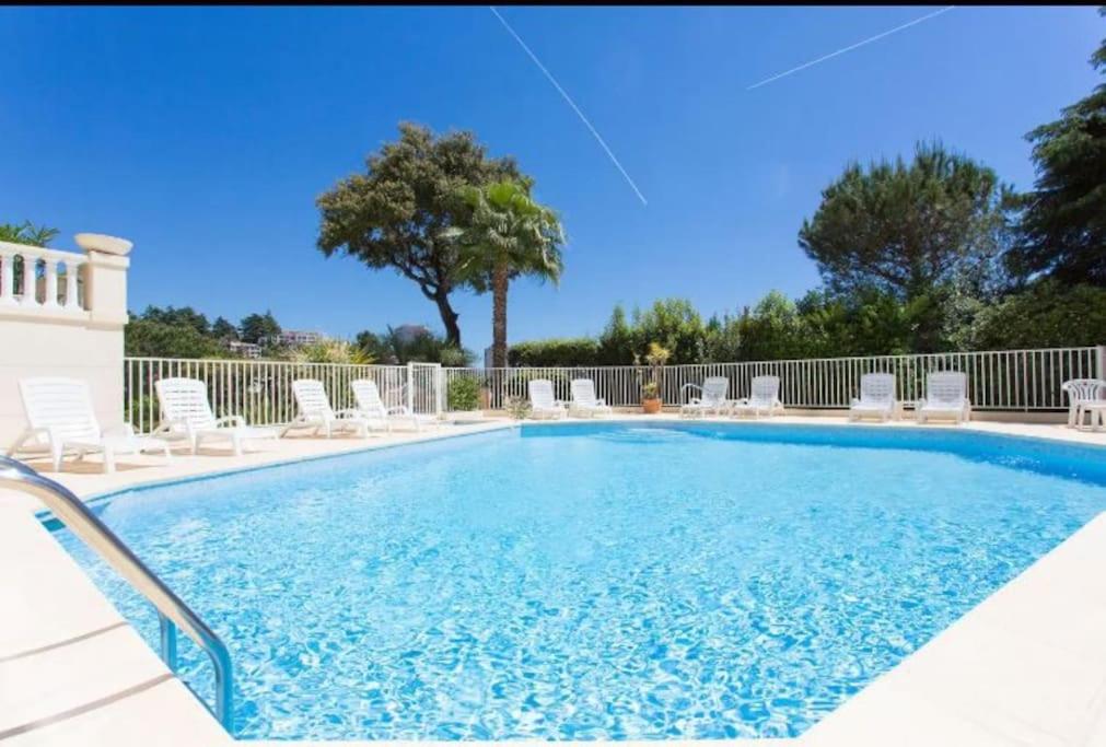 a large swimming pool with chairs and a tree at Résidence de luxe Sun Paradis, Studio terrasse, vue Mer Piscine Sauna in Cannes