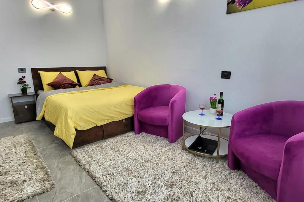 a bedroom with purple chairs and a bed and a table at Garsoniera centru vechi English park in Craiova