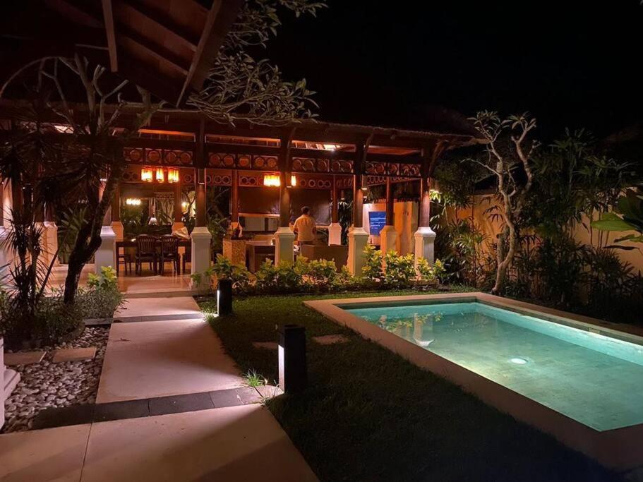 ein Schwimmbad vor einem Haus in der Nacht in der Unterkunft Jimbaran BeachStroll Villa (3BR) in Jimbaran